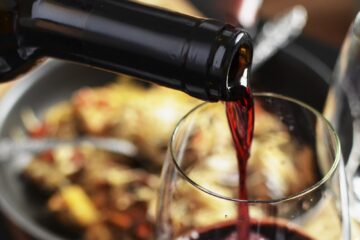 Vino rosso versato nel bicchiere durante una cena all'Enoteca Regionale di Ortovero